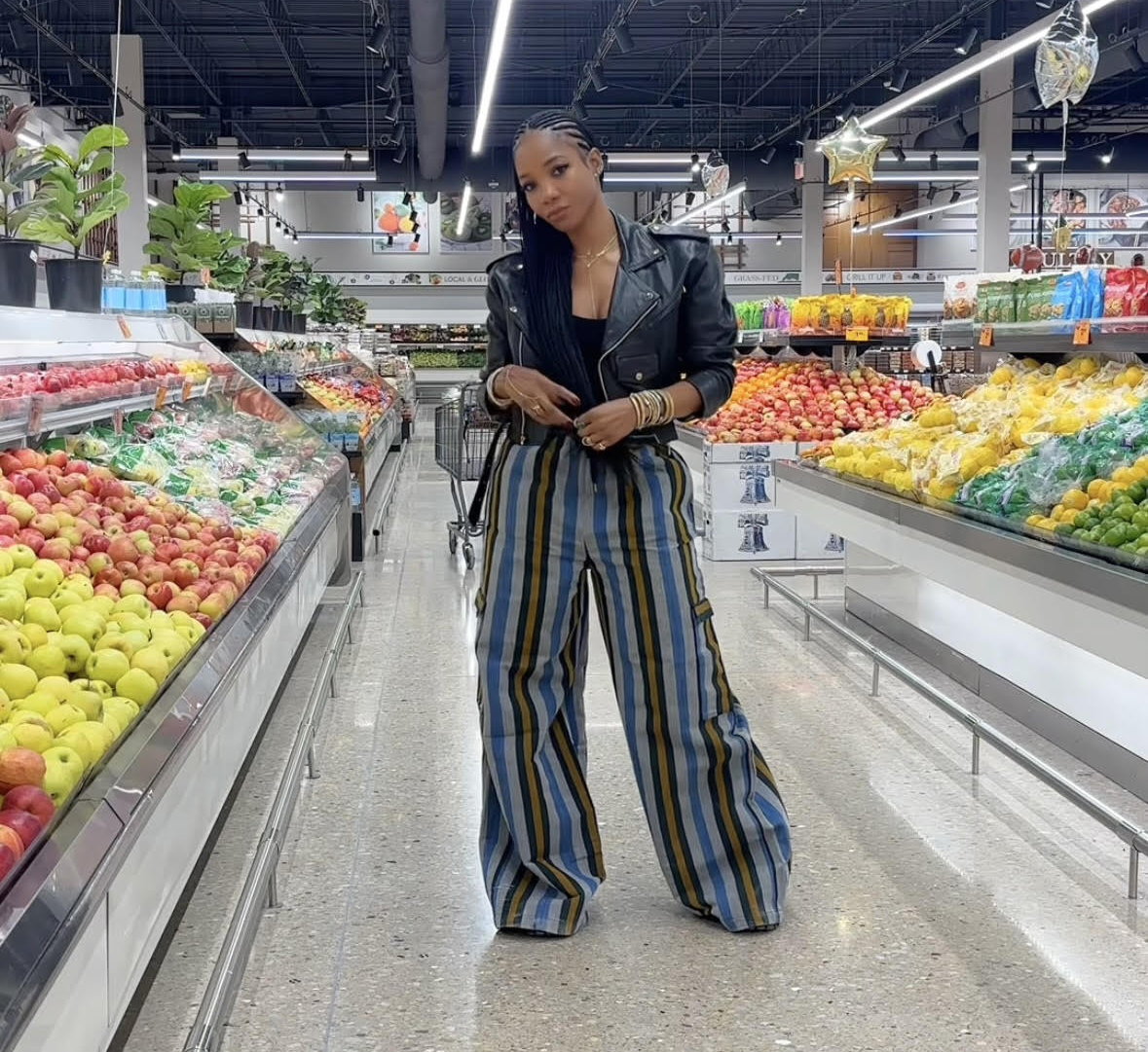Woman standing in a grocery produce aisle.