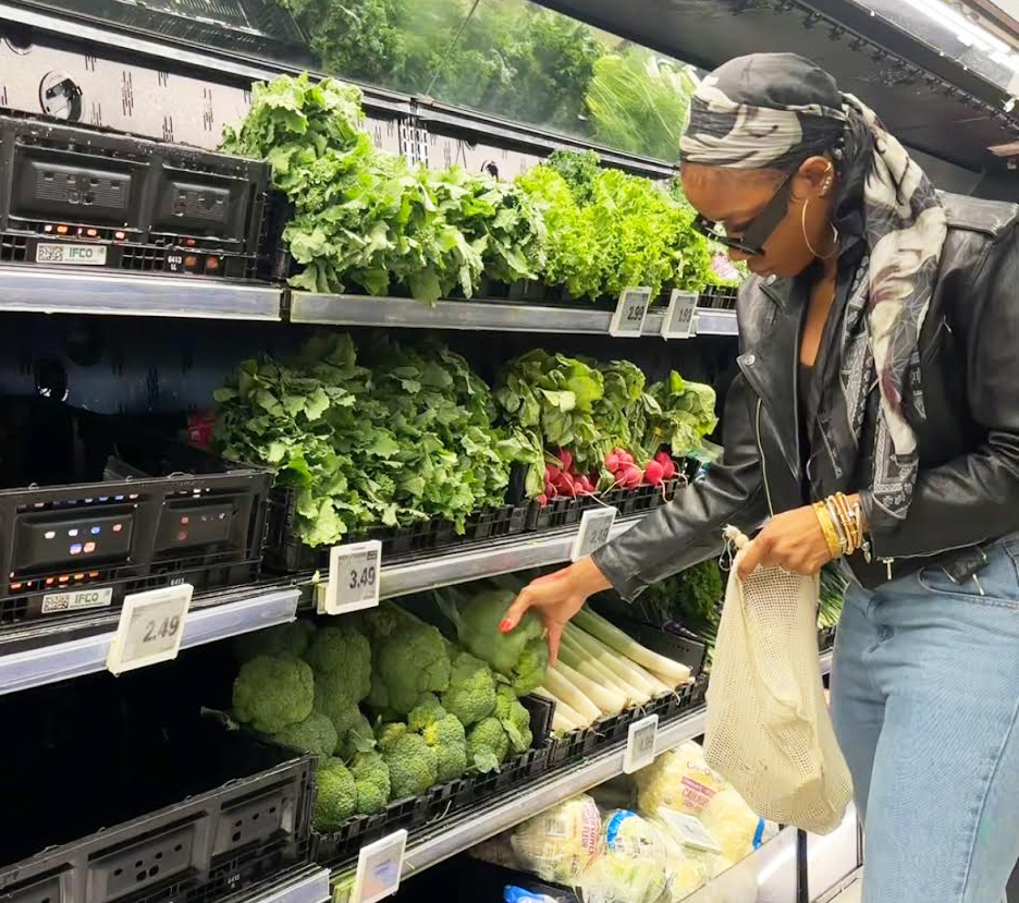 Woman choosing fresh vegetables in a grocery produce aisle.